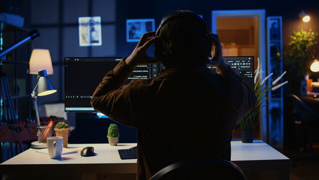 Technician putting headphones on while using coding to fortify firewalls, teleworking for IT company, computer scientist listening music and upgrading binary code scripts in home office.