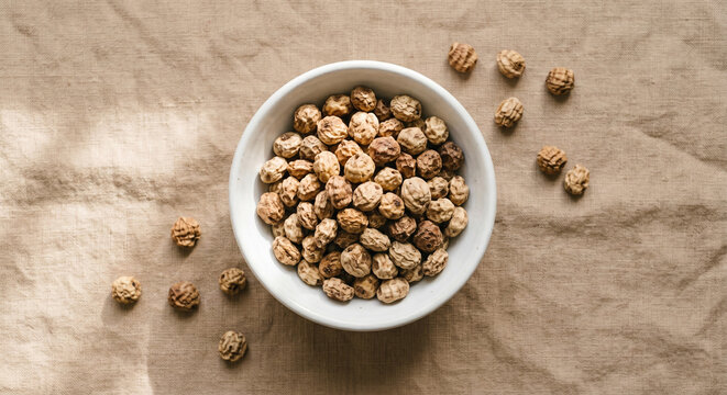 Dried Tigernuts in White Ceramic Bowl on Linen Surface