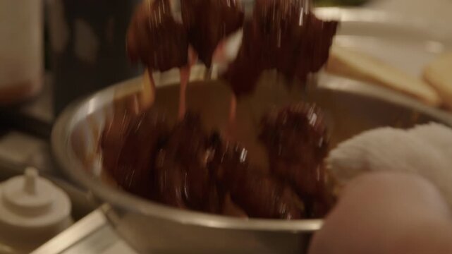 Slow motion chicken wings tossed in brown sauce bowl