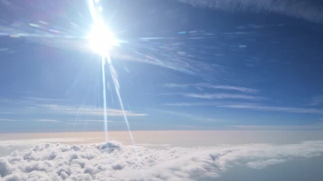 Spain Europe. 28.05. 2026. Video.  View from an airplane window with the early morning sun shining brightly through scattered clouds and a clear blue sky above