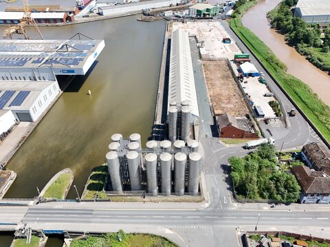 Aerial view of industrial metal silos situated along a canal next to a warehouse and road infrastructure in Goole, England, United Kingdom.