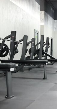 Row of bench press stations with plates in gym. Camera moving right