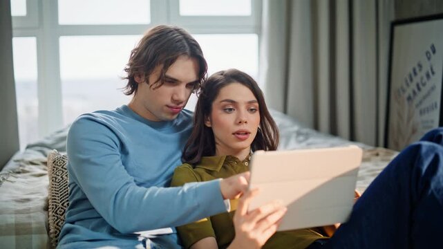 Relaxed teenagers using pad computer at home. Young girlfriend boyfriend bonding