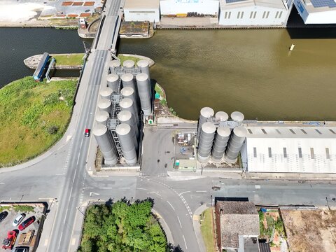 Aerial view of industrial metal silos situated beside a canal and a road bridge in the port town of Goole, England, United Kingdom.