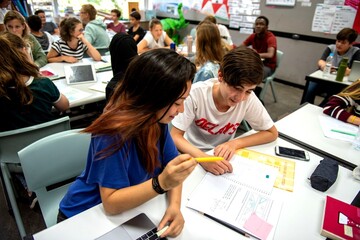Fototapeta na wymiar Students collaborating in a lively classroom setting with laptops.