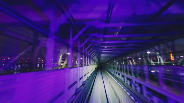 Train window view of riding through the illuminated Rainbow Bridge structure at night in Tokyo