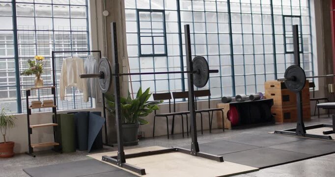 Camera is panning while squat rack with loaded barbell is staying centered, revealing gym layout