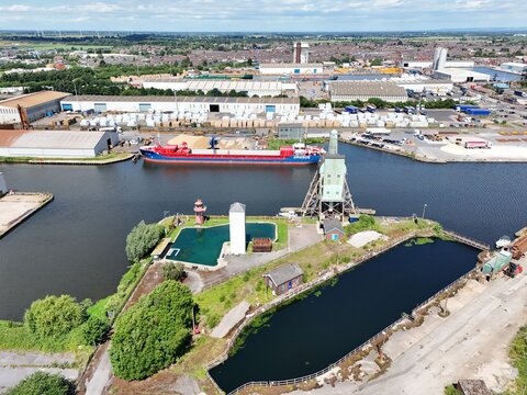 Aerial view of the historic Goole Docks featuring the iconic water tower, a cargo ship moored in the canal, and surrounding industrial warehouses in Goole, England, United Kingdom.