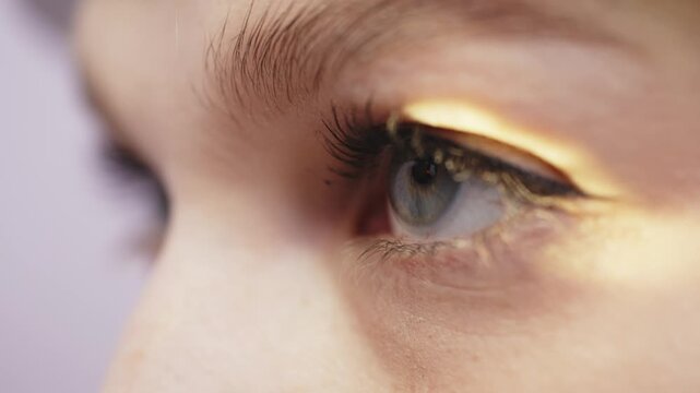Female patient undergoing eye examination as doctor inspects cornea with bright light, showcasing detailed view of eye and eyelashes in clinical setting