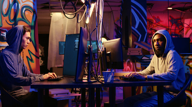 Portrait of security hackers exploring methods of breaching defenses and exploiting weaknesses in computer networks, malicious programmers in basement getting past firewalls.
