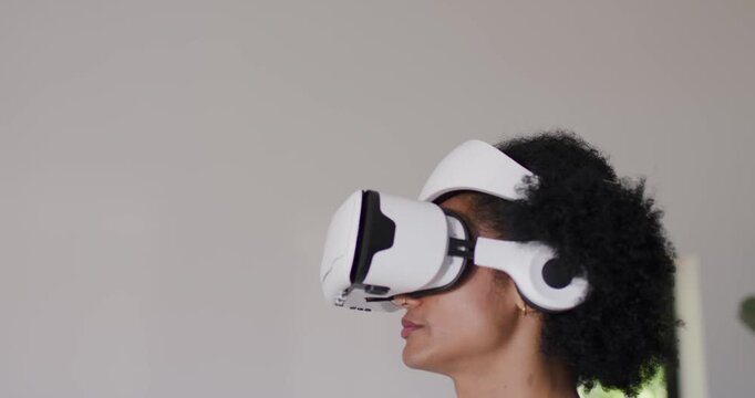 Man wearing white VR headset by window, following cue, raising right index finger, copy space