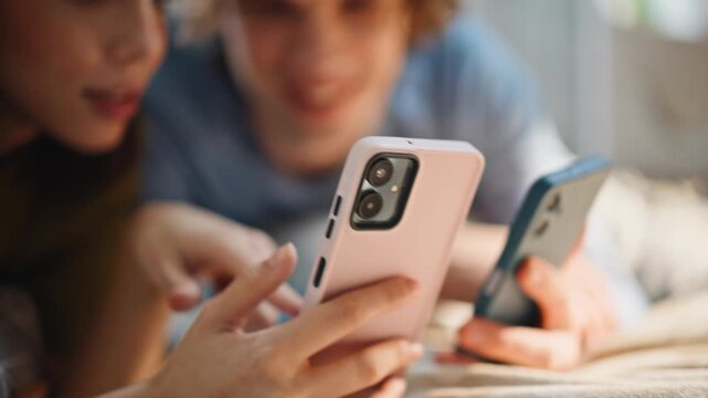 Hands holding two smartphones closeup. Laughing couple holding mobile devices