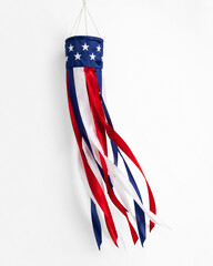 Hanging patriotic windsock with stars and flowing red white and blue satin ribbons on white background, festive outdoor decoration for summer holidays.
