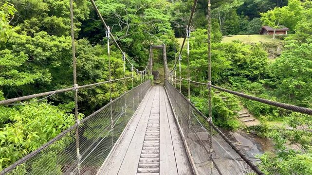 The suspension bridge and unique granite riverbed with potholes at Ayumodoshi Natural Park on Tsushima Island, Nagasaki Prefecture, Japan.