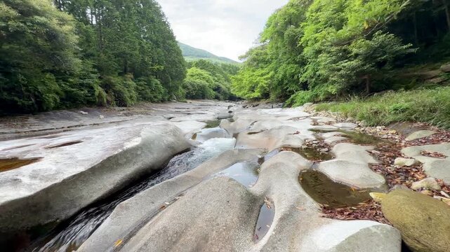 The suspension bridge and unique granite riverbed with potholes at Ayumodoshi Natural Park on Tsushima Island, Nagasaki Prefecture, Japan.