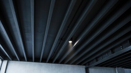 Fototapeta premium Concrete ceiling beams form a dark architectural pattern while a single spotlight casts a bright glow on the grey surface.