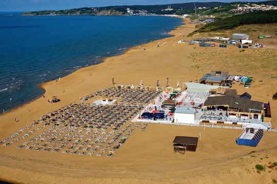 Aerial view of Kilyos shore featuring organized rows of sun loungers on a sandy beach with a beach club facility and the Black Sea in the background in Sariyer, Istanbul, Turkey.