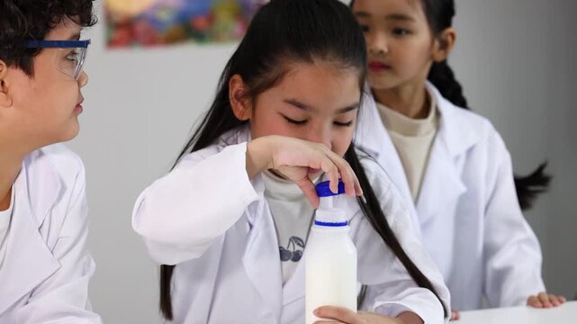 Asian Children in Lab Coats Conducting Science Experiment with Milk Bottle