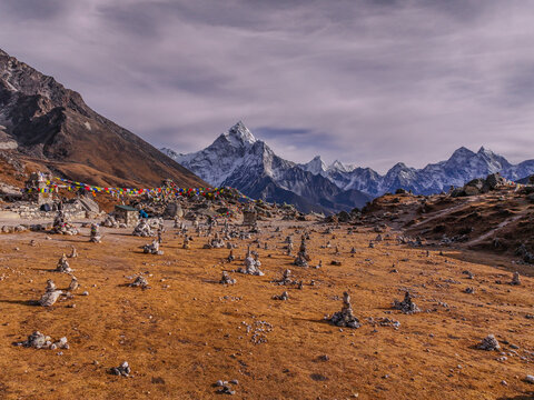Aerial view of Everest Base Camp featuring colorful prayer flags, numerous stone cairns scattered across the barren landscape, and snow-capped Himalayan peaks in Khumjung, Koshi Province, Nepal.