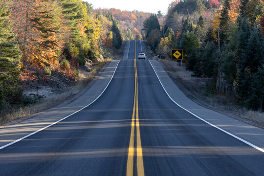 Hilly scenic autumn highway in Algonquin Provincial Park Ontario Canada with moose wildlife warning road sign