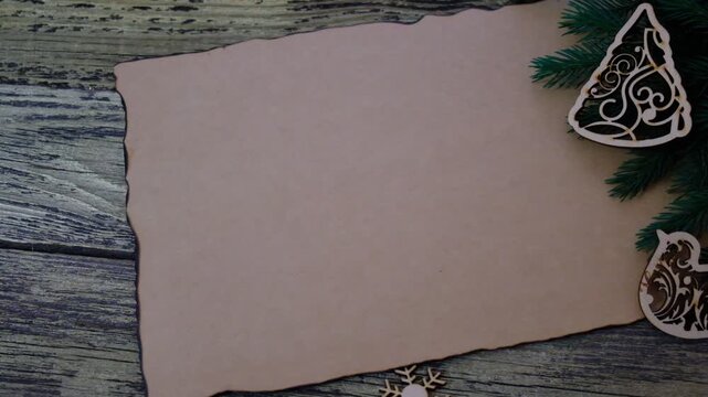 Christmas tree and decorations. Craft beige weathered brown paper with burn marks and uneven edges rests on a dark golden brown wooden table or wall. Postcard.Copy space, free space for text. Mockup. 