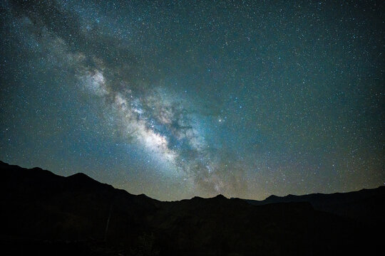Aerial view of the Milky Way galaxy stretching across the starry night sky above the dark silhouettes of the Himalayan mountains in Nepal.