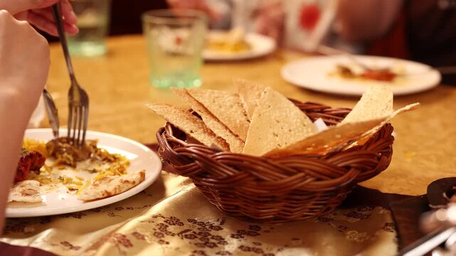 Close Up of Person Eating Indian Food with Papadum Basket