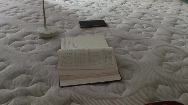 Book pages blowing in the wind on bed with moody window light