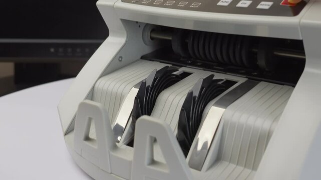Close up jib shot, electronic money counting machine with digital display processing 100 Dollar bills, soft focus, slow motion