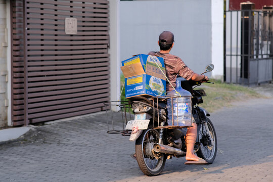 Man riding old motorbike to deliver mineral water from grocery shop in Yogyakarta, June 19, 2026