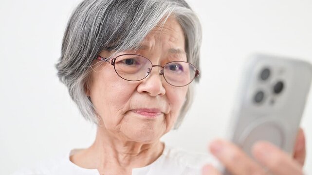 老眼鏡でスマホを見るグレイヘアのシニア女性　文字が見えにくい動画