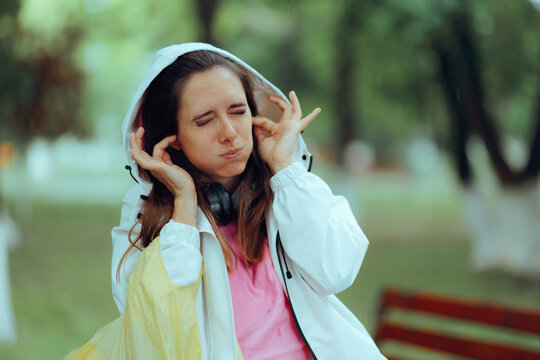 Distressed Woman Covering Her Ears From Thunder On Rainy Day. Scared female plugging her ears with fingers during intense stormy weather outdoors