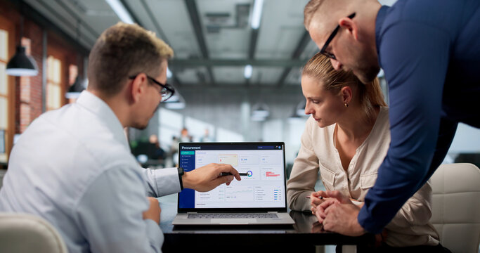 Procurement Manager Guiding Diverse Team Using Laptops