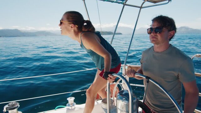 Sailing in the smooth sea during sunny day. Man and woman sail the small sailing boat in the region of the island of Ilha Grande in Brazil