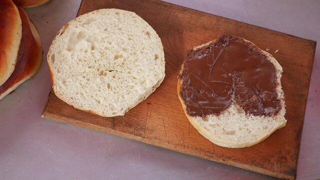 Baker prepares a slice of bread and spreads chocolate on it