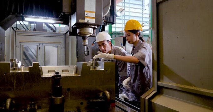 Asian engineer team checks CNC machine interior, guiding fixture setup, tool position, safety clearance, machining sequence, production readiness in connected , slow motion scene.