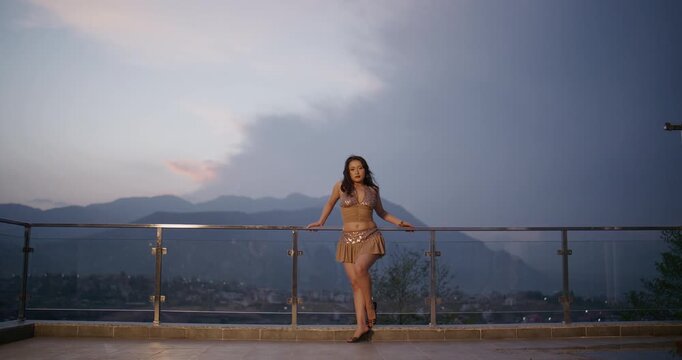 Fashion Model in Gold Sequin Two-Piece on Terrace Overlooking Hillside Town	