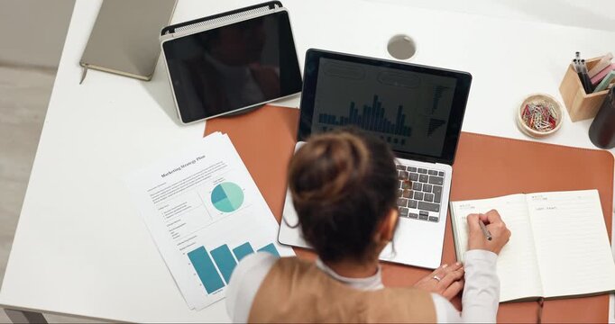 Laptop, woman and writing in office with notebook, HR data and analysis of employee retention rate. Above, person and computer in business with human resources stats, graphs and staff turnover notes.