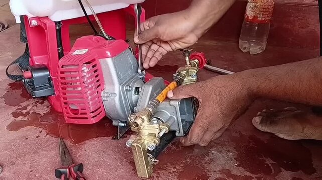 Close Up Of Mechanic Tightening Hex Bolts To Secure Pressure Pump Onto Gasoline Engine For Power Sprayer Assembly

