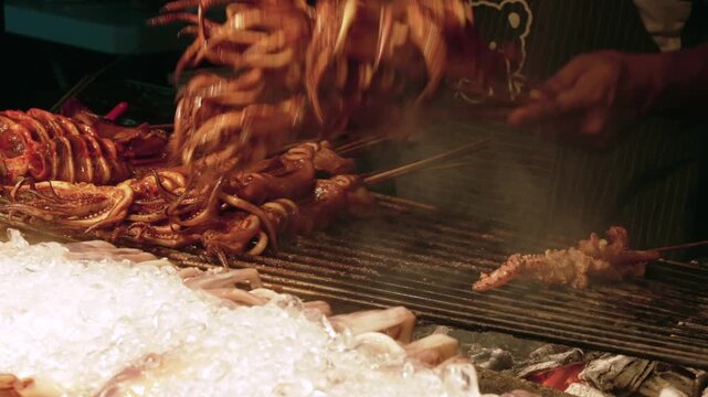 Close up chef cooking Fresh squids on grill at Night Seafood Market Stall