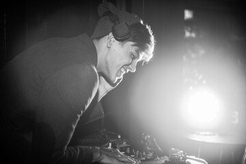 DJ performing live set with headphones in dim lighting © Rawpixel.com
