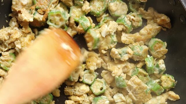 Stir-frying scrambled eggs with sliced okra in a hot pan. Thai food