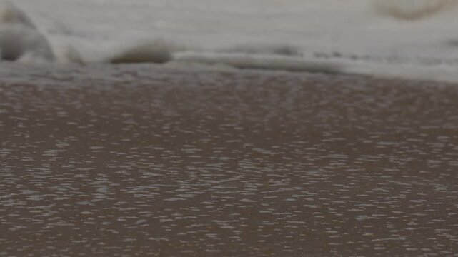 close up of waves washing up on the sand