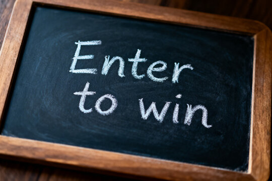 Enter to Win Text Written in White Chalk on Vintage Blackboard with Wooden Frame