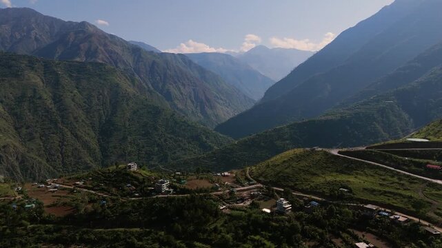 Wide angle aerial shot of rugged mountain range slopes with sharp switchback road cutting across ridges