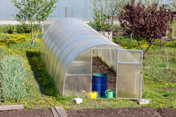 Obraz premium Greenhouse stands in sunny garden bed