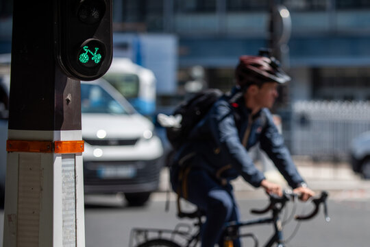 Green bicycle traffic light signal with cyclist in background, Paris