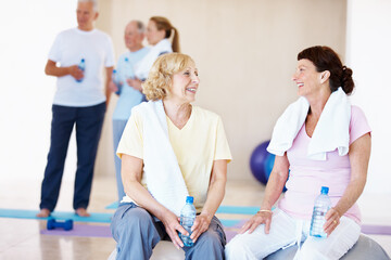 Naklejka premium Fitness, happy or old women in class with break, cardio rest or bonding in workout hobby. Smile, cool down or friends in center with water bottle, team connection or recovery in retirement training.