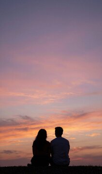 Captures Silhouette Of Two Individuals Sitting Closely Together Against Backdrop Sunset Sky Person On Left To Long Hair Suggesting Female Individual