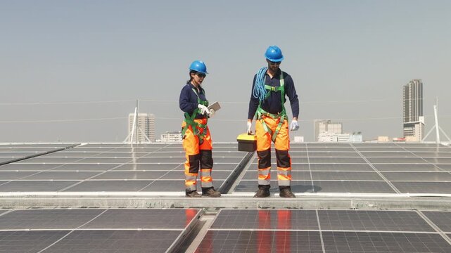 Two solar technicians inspecting rooftop photovoltaic panels, one adjusting panel alignment while colleague points and checks installation details.